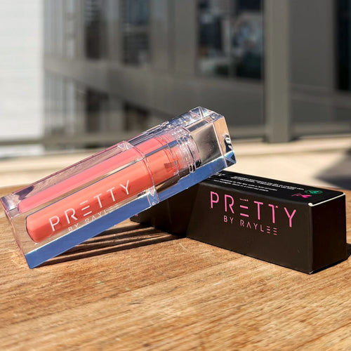 Lip gloss with packaging on a wooden surface with a cityscape background